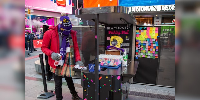 A Times Square worker disinfects a booth where people can write their New Year wish on scraps of paper that will rain at the crossroads of the world on New Year's Eve.